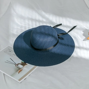 Detailed texture of dark blue woven straw hat with elegant black satin ribbon detail