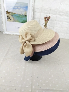 Detailed texture of woven straw sun hats with large decorative bows in various colors