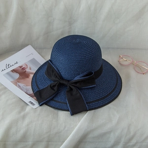 Detail of the fine weave and black satin bow on the elegant navy blue straw hat