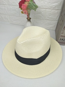 Close-up of beige woven straw fedora hat with a classic wide black ribbon band
