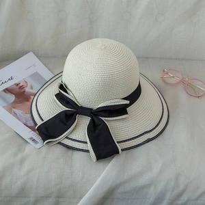 Elegant beige straw sun hat with black bow and wide brim for beach vacations