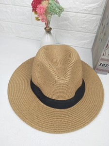 Close-up of natural straw weave texture and black ribbon band on a classic summer fedora hat