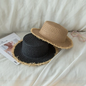 Close-up of flat-top straw hats in black and khaki with trendy frayed raw edges