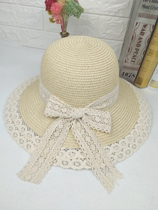 Détail d'un chapeau de paille beige avec bordure en dentelle blanche et grand nœud