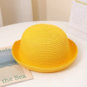 Détail d'un chapeau de soleil jaune en paille tressée avec bord roulé et texture spirale