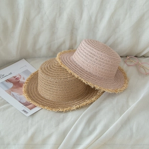 Detail of light khaki and pink flat-top straw hats with fringe edges and summer accessories