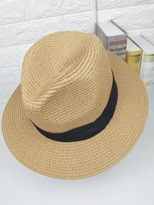 Detail of classic straw fedora hat featuring fine spiral weave and black grosgrain ribbon