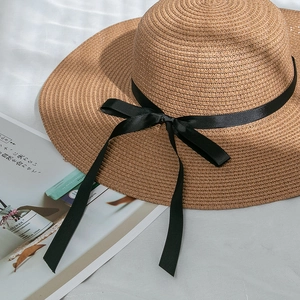 Detailed macro view of woven paper straw texture and black ribbon bow on sun hat