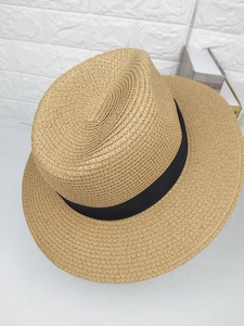 Detail of light brown straw fedora hat featuring a classic black ribbon band and wide brim