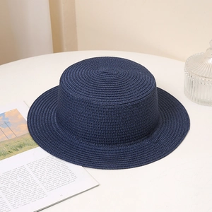 Detail of navy blue straw boater hat showing spiral weave texture on a white table