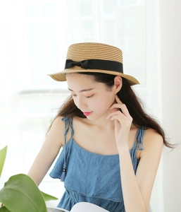 Dettaglio di un cappello di paglia intrecciato marrone chiaro con fiocco nero
