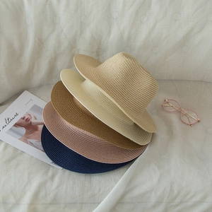 Flat lay of woven straw sun hats in beige, brown, and navy for summer beach travel