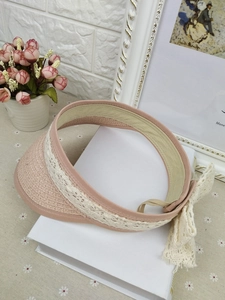 Detail of a pink straw sun visor for girls featuring lace trim and a large bow