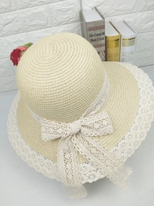 Détail d'un chapeau de paille beige avec dentelle blanche délicate et un grand nœud décoratif