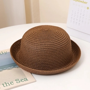 Détail de la texture du chapeau de paille marron foncé et du bord roulé sur table