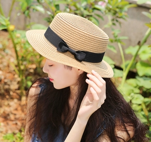 Dettaglio della trama del cappello di paglia a testa piatta con nastro nero e fiocco