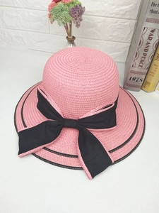 Top view of pink woven sun hat with black bow and elegant ribbon edge detailing