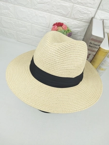 Detail of khaki woven straw fedora hat featuring a black ribbon and breathable texture
