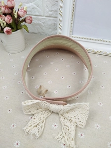 Detailed close-up of straw sun hat featuring a large lace bow and elastic strap