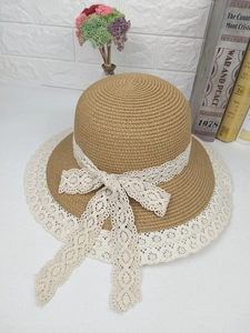 Détail d'un chapeau de paille kaki avec tissage complexe et grand nœud en dentelle blanche