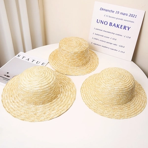 Detailed view of three hand-woven wheat straw boater hats with flat tops and tight textures