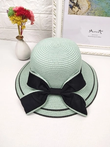 Detailed texture of woven straw sun hat with a large black bow and decorative trim