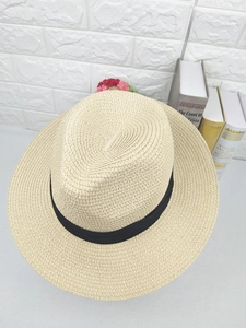 Detailed view of cream straw fedora hat featuring fine woven texture and black ribbon band
