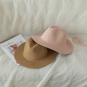 Detail of khaki and pink woven straw fedoras with fine texture on a textured fabric sofa