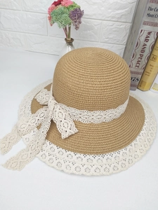 Détail de la paille tressée naturelle avec bordure en dentelle blanche et nœud sur chapeau