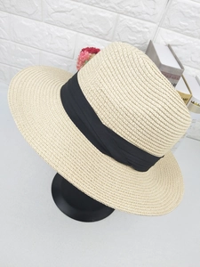 Close-up of a beige straw fedora with a black ribbon band and decorative knot