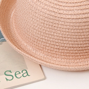 Gros plan sur la texture tissée fine et le matériau en paille rose-orange du chapeau