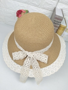 Détail du chapeau de paille kaki avec bordure en dentelle blanche et nœud élégant