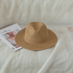 Detailed close-up of breathable straw sun hat with tight weave texture on cream sofa