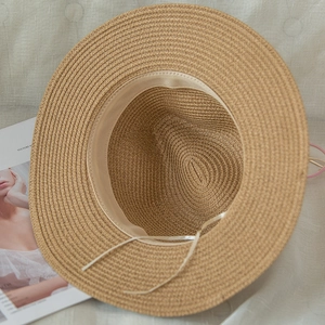 Detail of light brown straw hat interior featuring a white sweatband and adjustable drawstring