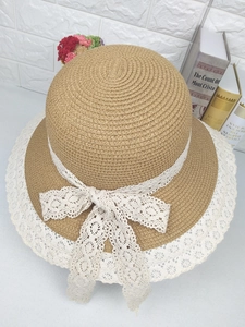Détail d'un chapeau de paille avec bordure en dentelle florale et grand nœud blanc