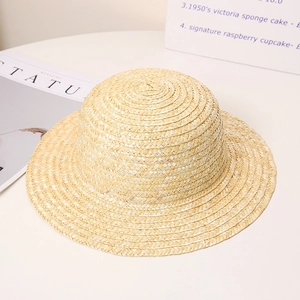 Classic wide brim straw hat with spiral weave on a minimalist white desk with magazines