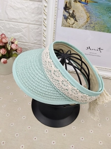 Detail of mint green straw visor for girls featuring white lace trim and decorative bow
