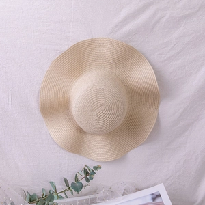 Close-up of wavy brim straw hat with spiral woven texture on white fabric backdrop