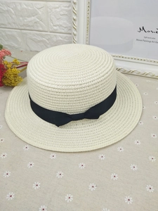 Dettaglio del cappello di paglia intrecciata con corona piatta e fiocco in nastro nero