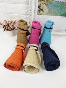 Detail of six colorful straw sun hats in folded storage state with elastic bands