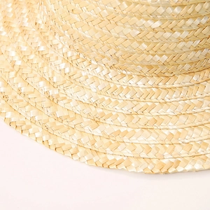 Detailed macro view of spiral woven natural wheat straw texture on a flat top boater hat