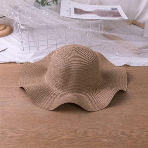 Detailed view of the woven texture and wavy brim on this khaki sun protection straw hat