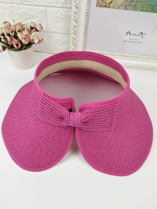Detail of fuchsia woven sun visor hat featuring a large brim and stylish back bow
