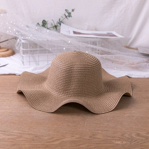 Detailed view of the wavy wide brim on a dark khaki straw sun hat for summer