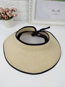 Detail view of woven straw sun visor with black fabric trim and adjustable bow tie