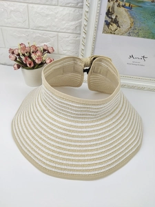Detail view of foldable straw sun hat with beige and white stripes on a neutral background