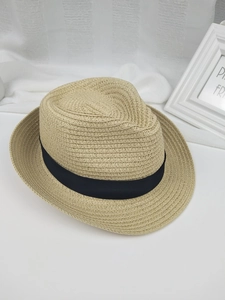 Détail d'un chapeau de paille naturel avec ruban noir et texture tissée sous lumière douce