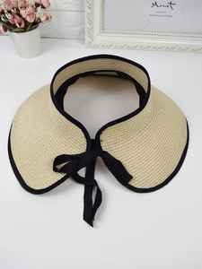 Detailed top view of beige straw visor with black trim and a bow on white background