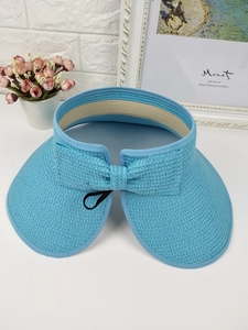 Close-up of a light blue straw sun visor featuring a large brim and a woven bow at the back