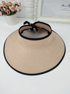 Detail of beige straw sun visor with black ribbon trim and elegant rear bow tie